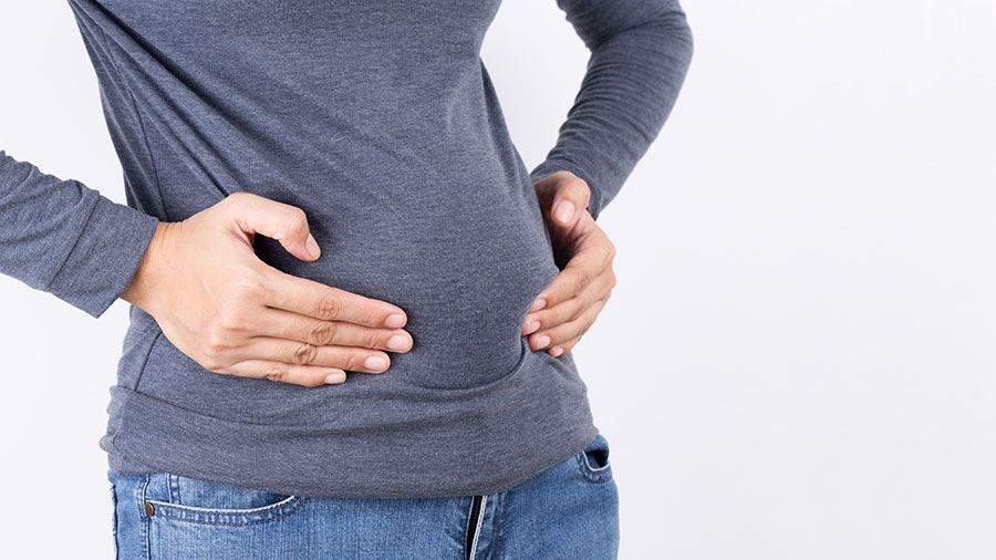 A woman indicating to her postpartum belly fat.